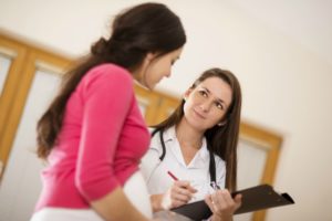 Young pregnant woman with doctor in ambulance.